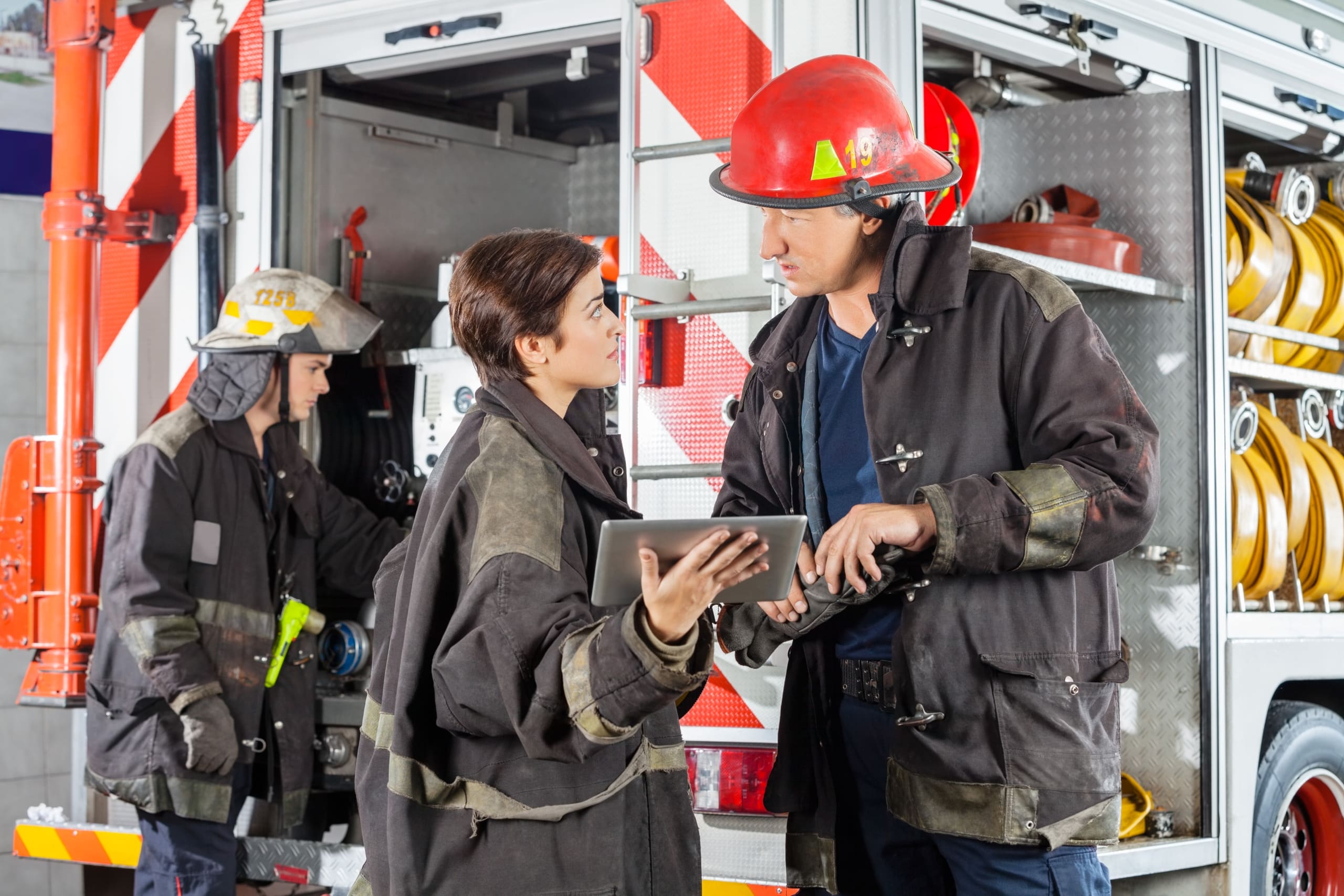 Firefighters Discussing Over Digital Tablet Against Truck