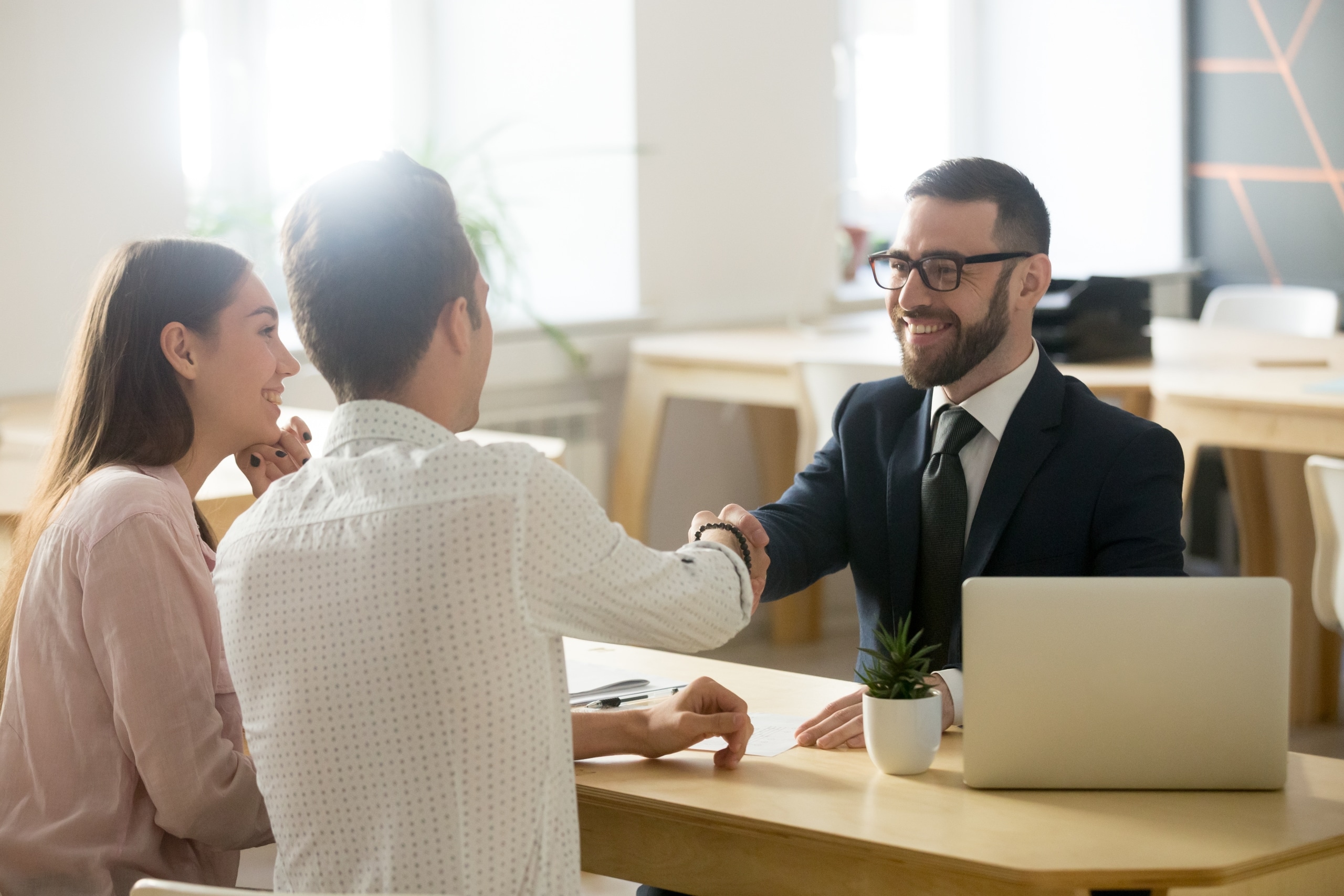 smiling man shaking hands with couple at bank