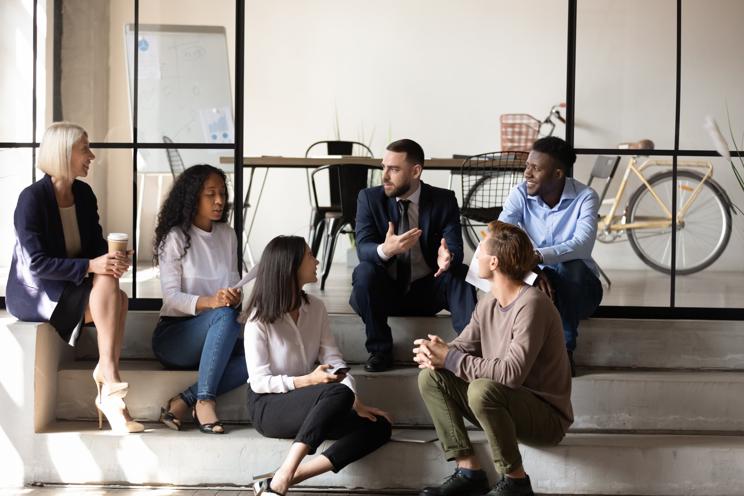 Diverse, happy employees chatting and sitting on stairs