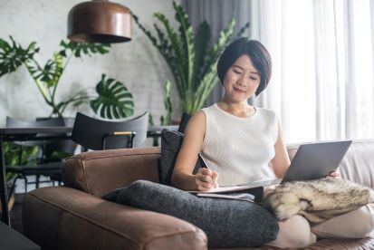 Happy Woman Working From Home Using Laptop and Pen