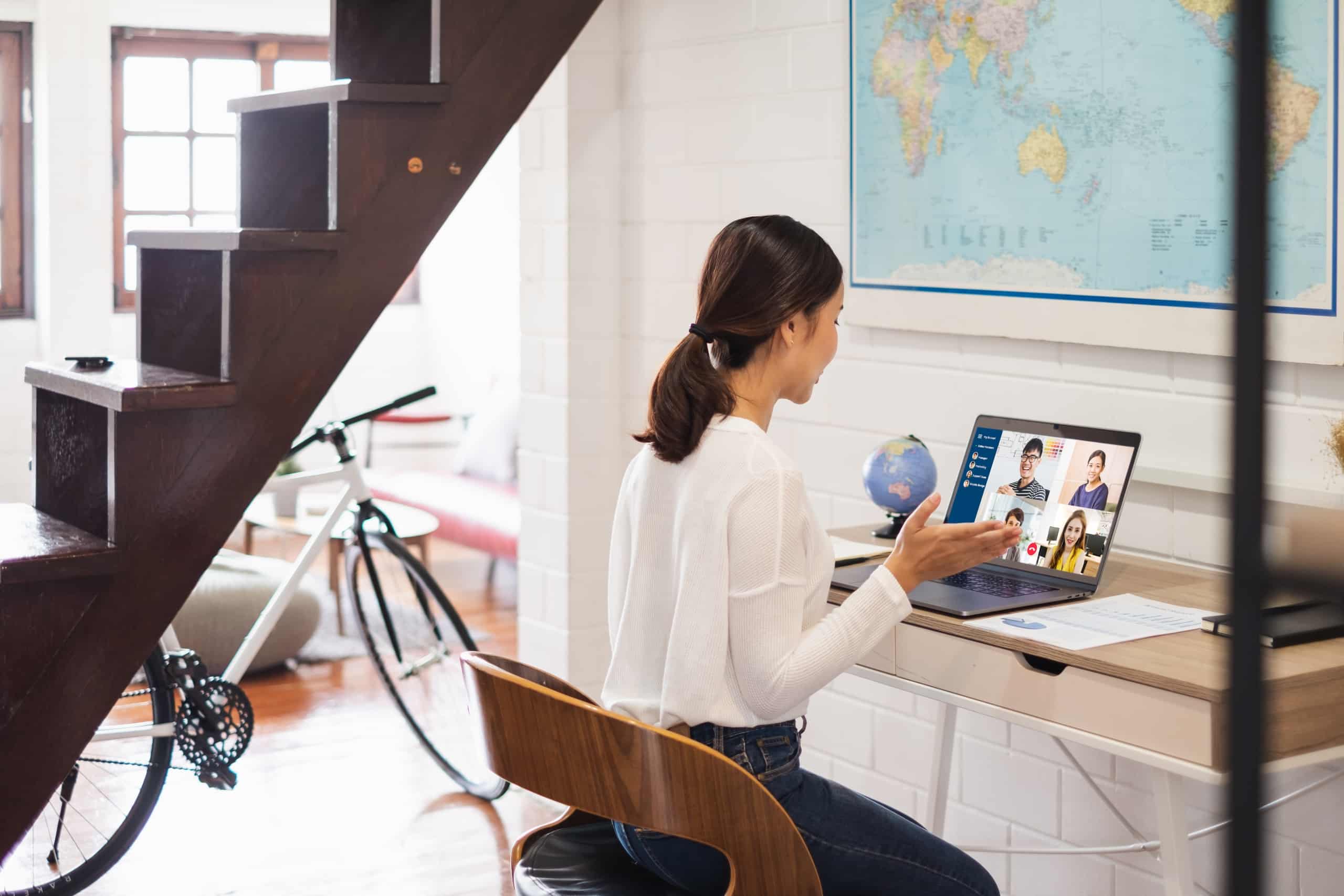 Young woman working with team remotely on laptop