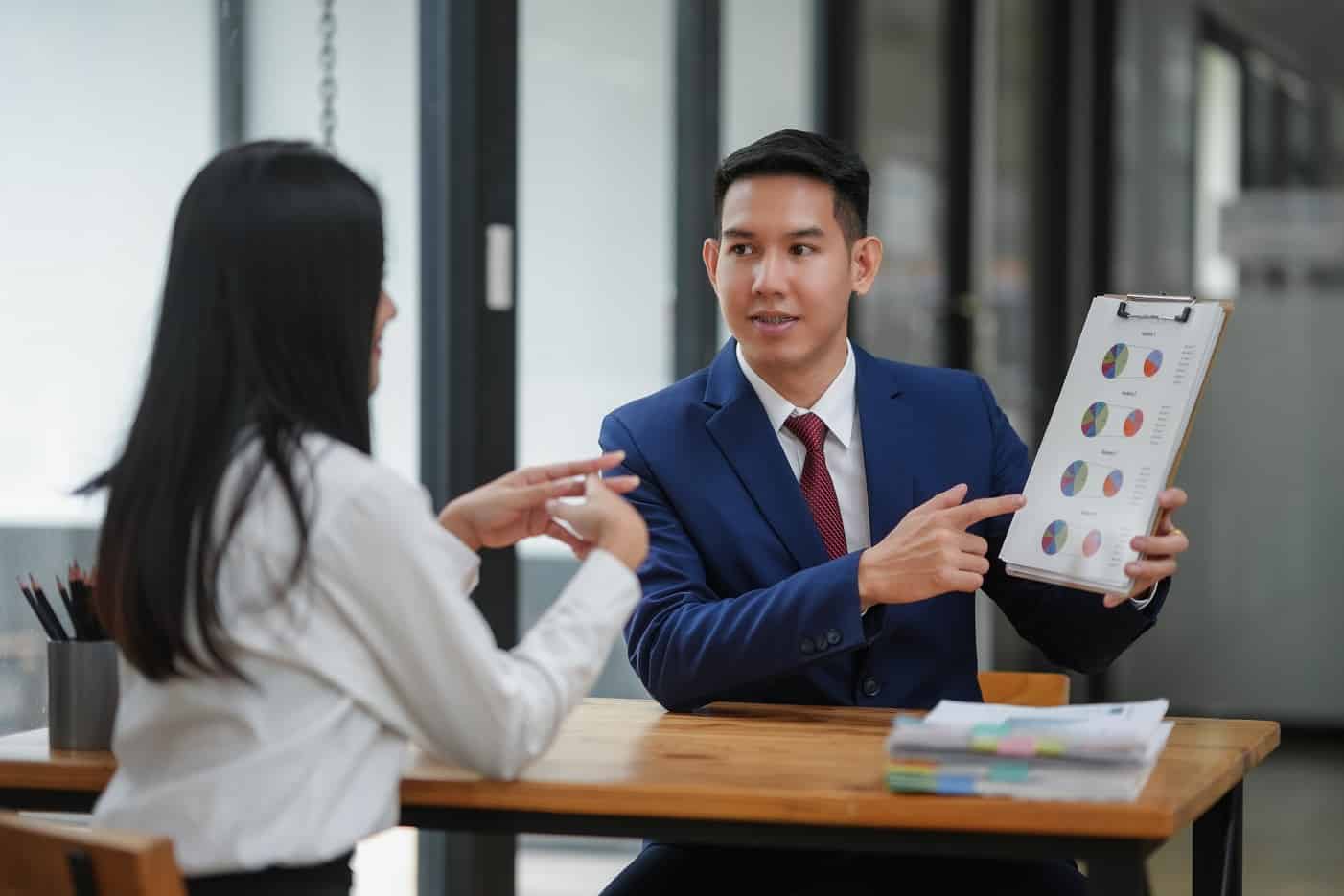 Two professionals discussing project details at the office. Man showing document to woman in a consultative meeting.